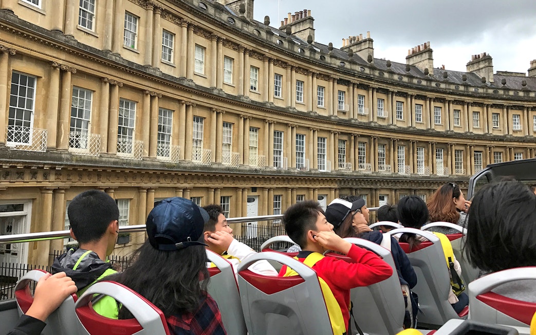 Open-top bus tour passing the Royal Crescent in Bath, England.
