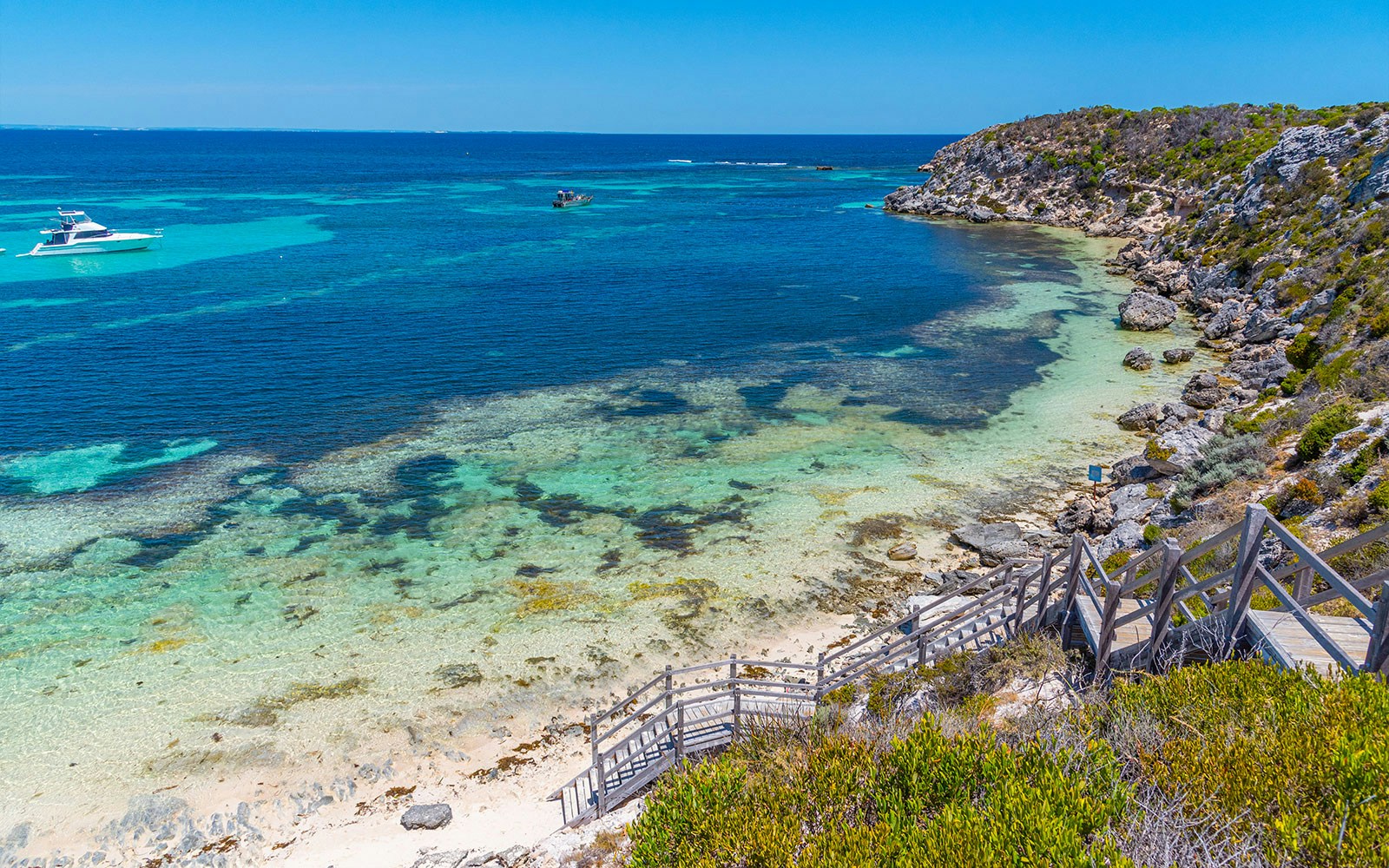 Coastal view of Rottnest Island, Australia, with clear turquoise waters and a wooden staircase leading to the beach.
