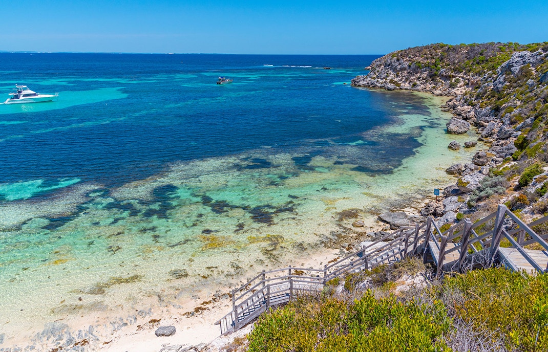 Coastal view of Rottnest Island, Australia, with clear turquoise waters and a wooden staircase leading to the beach.