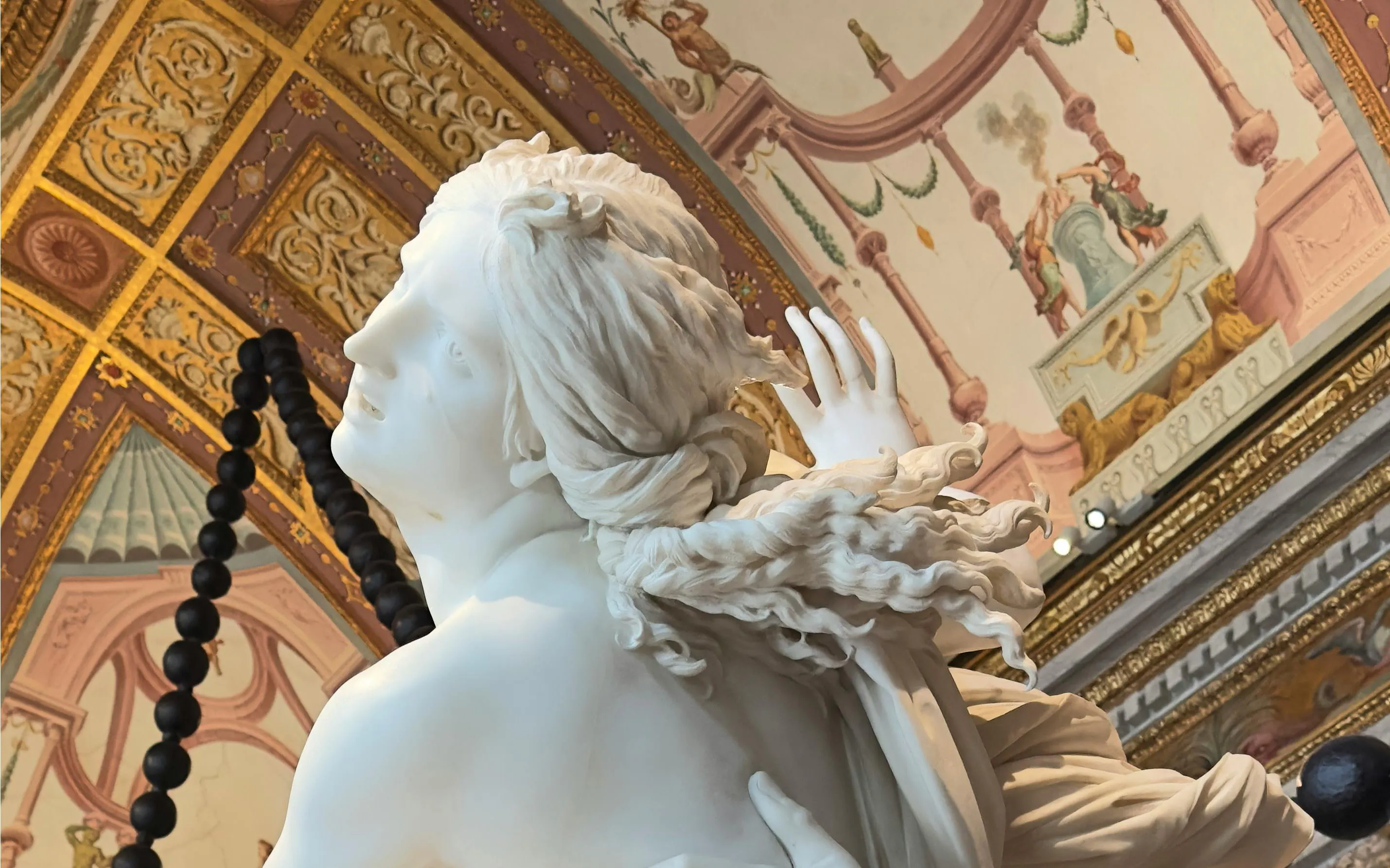 Bernini's "The Rape of Proserpina" sculpture detail in ornate gallery setting.