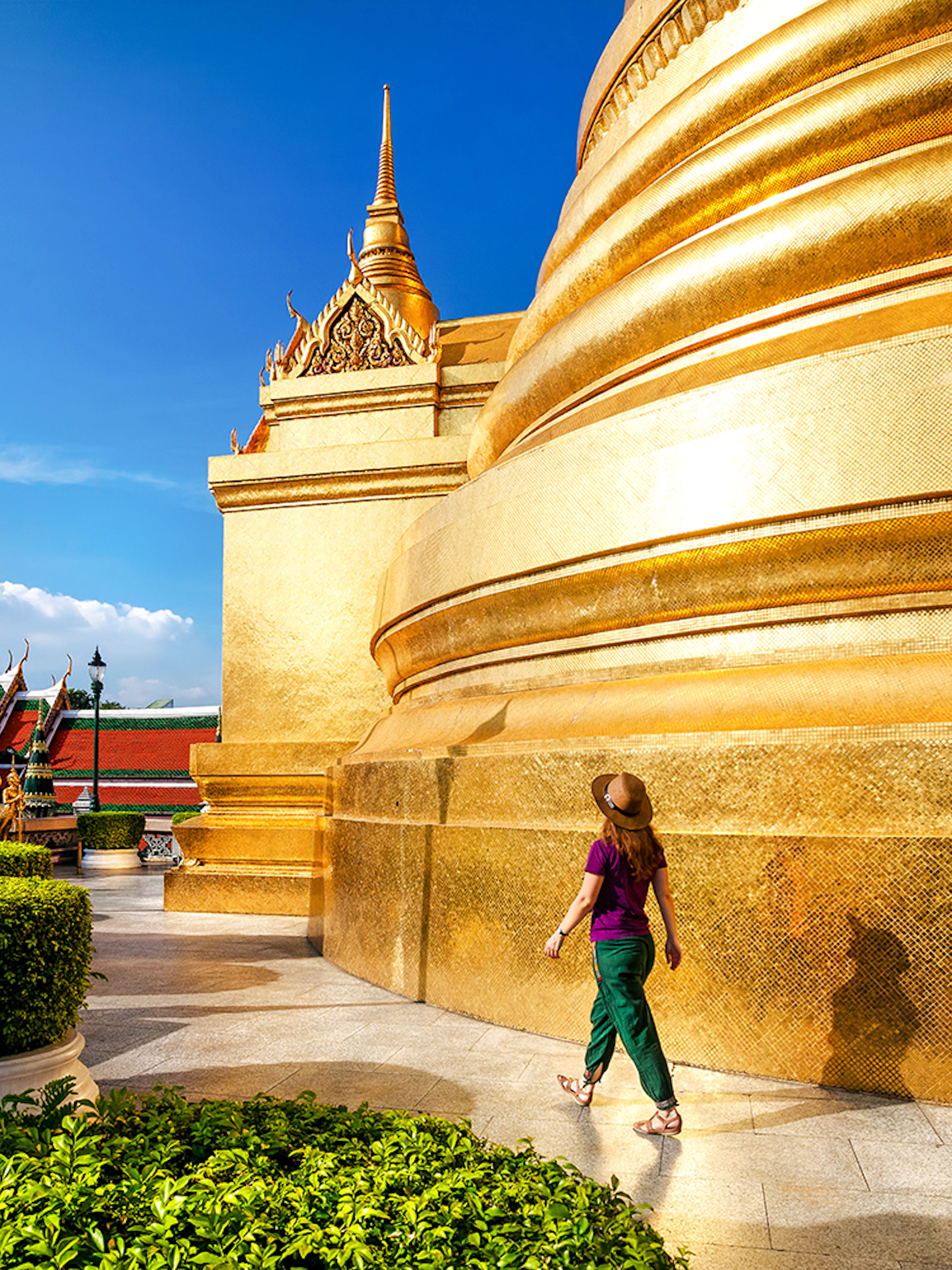 Woman walking near golden stupa at Wat Phra Kaew, Bangkok.