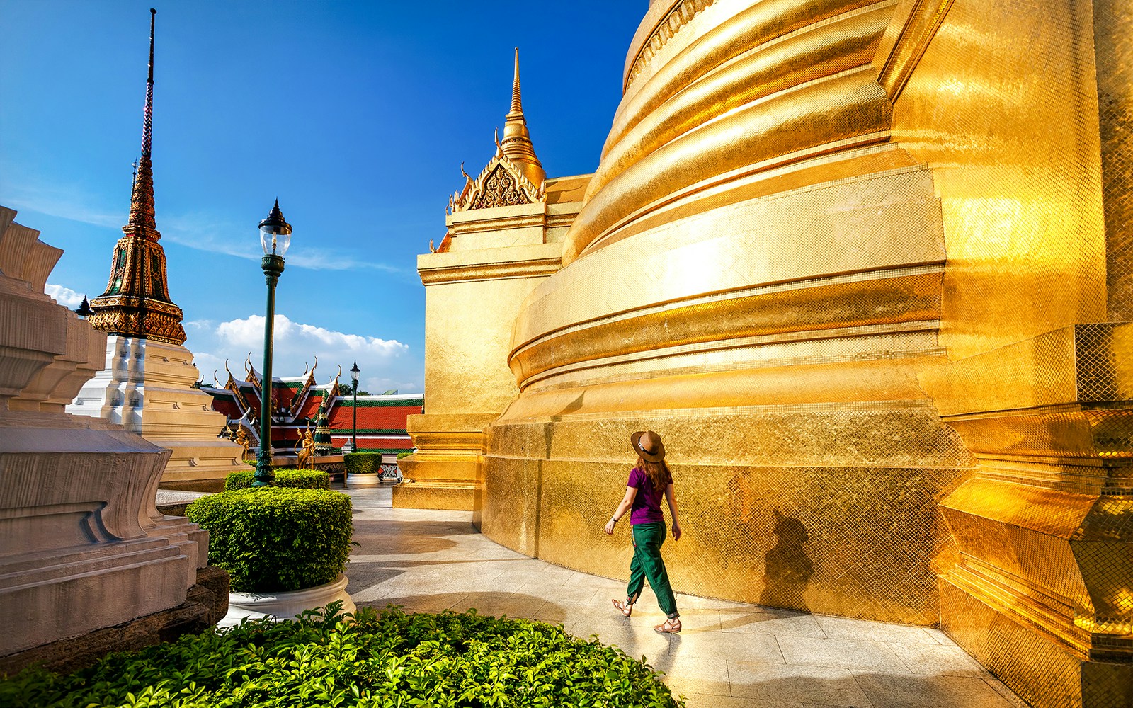 Woman walking near golden stupa at Wat Phra Kaew, Bangkok.