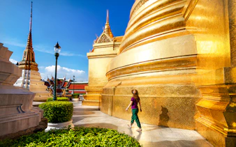 Woman walking near golden stupa at Wat Phra Kaew, Bangkok.