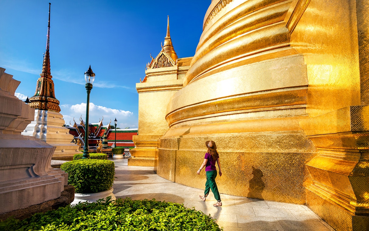 Woman walking near golden stupa at Wat Phra Kaew, Bangkok.
