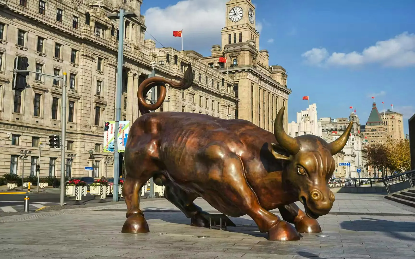 Bronze bull statue on the Bund in Shanghai, China, with historic buildings in the background.
