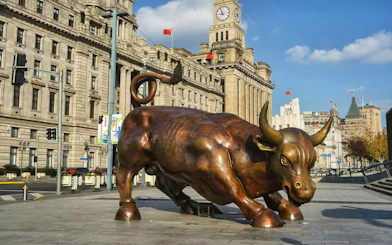Bronze bull statue on the Bund in Shanghai, China, with historic buildings in the background.