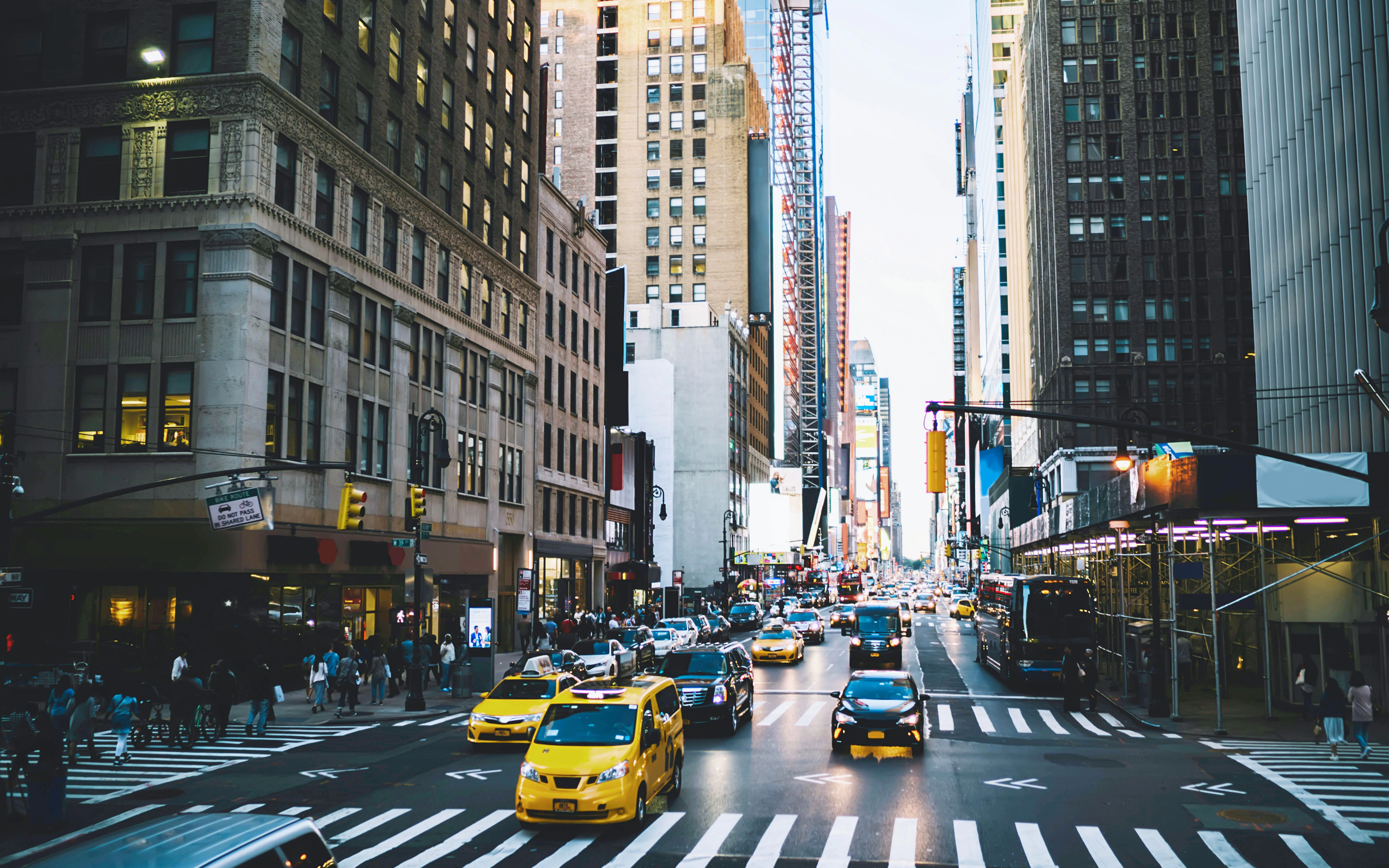 Midtown Manhattan street view with skyscrapers, busy traffic, and pedestrians on Broadway Avenue.