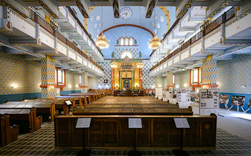 Interior of Kazinczy Synagogue in Budapest, featuring ornate balconies and chandeliers.