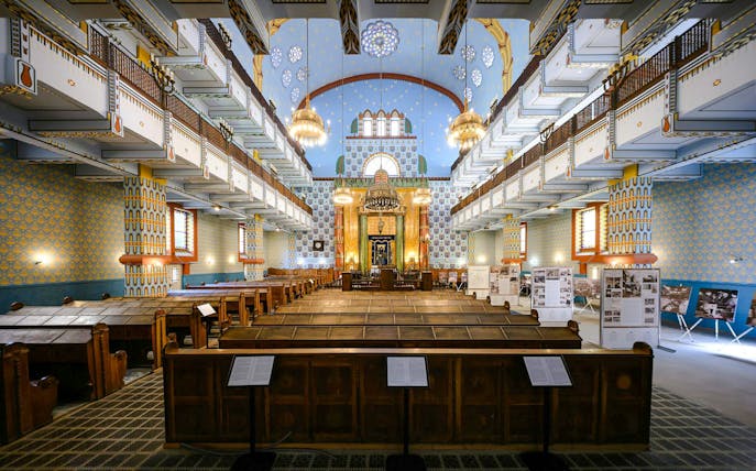 Interior of Kazinczy Synagogue in Budapest, featuring ornate balconies and chandeliers.