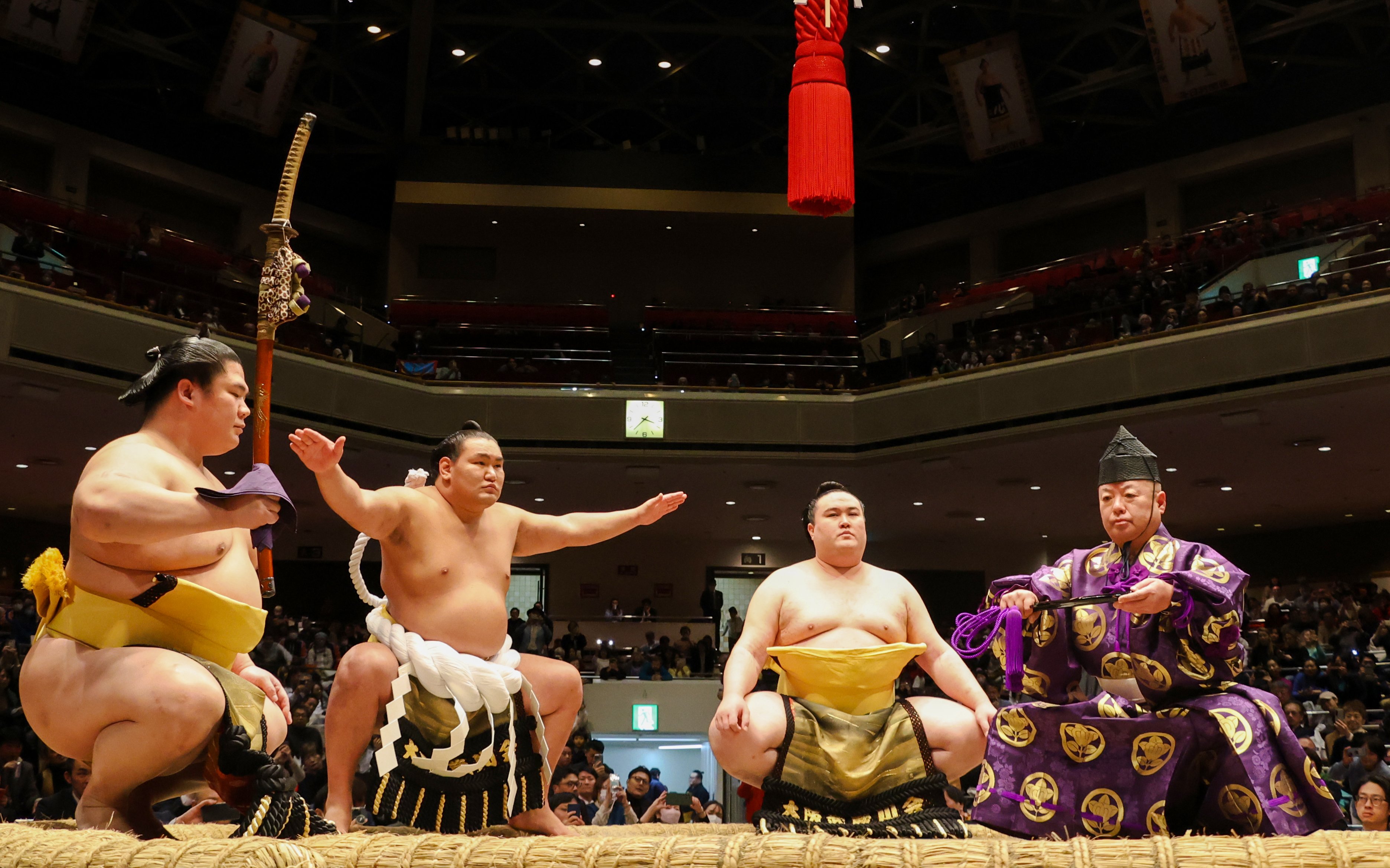 Sumo wrestlers performing a ritual in a Japanese arena.