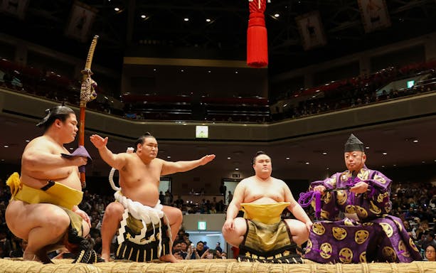 Sumo wrestlers performing a ritual in a Japanese arena.