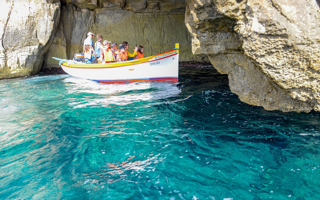 Small boat with tourists exploring the Blue Grotto cave in Capri, Italy.
