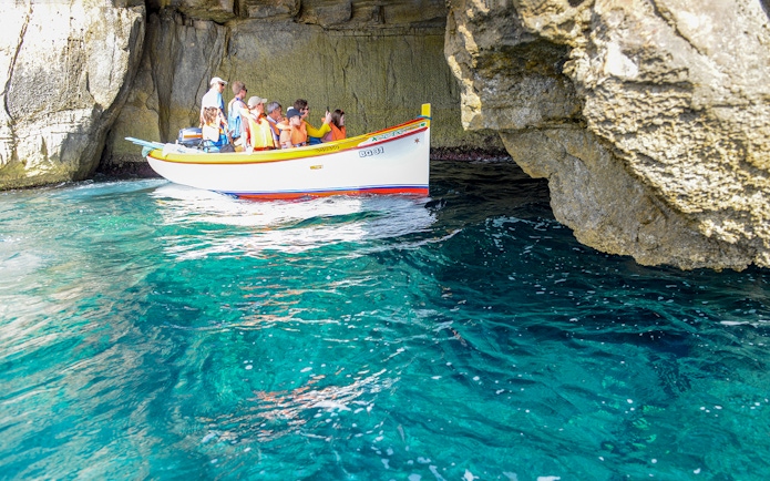 Small boat with tourists exploring the Blue Grotto cave in Capri, Italy.