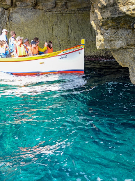 Small boat with tourists exploring the Blue Grotto cave in Capri, Italy.