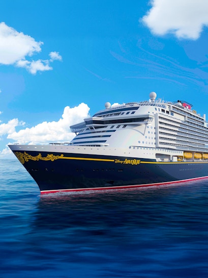 Disney cruise ship sailing on open sea under clear blue sky.