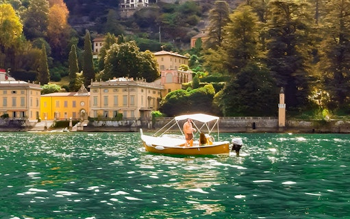 Boat on Lake Como with historic villas in the background.
