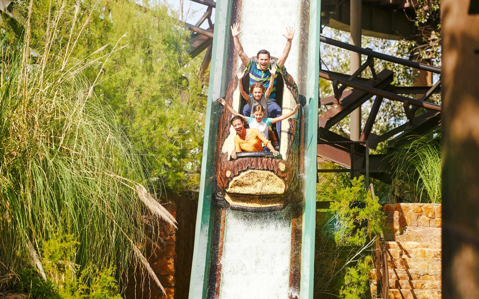 Visitors enjoying the Silver River Flume ride at PortAventura amidst lush greenery.