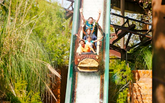 Visitors enjoying the Silver River Flume ride at PortAventura amidst lush greenery.