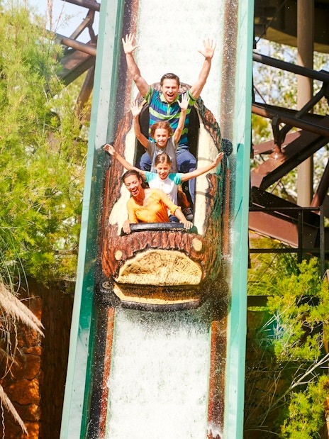 Visitors enjoying the Silver River Flume ride at PortAventura amidst lush greenery.