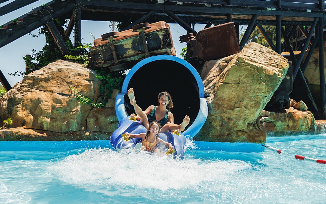 Tornado water slide at Western Water Park with people splashing into the pool.