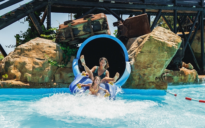 Tornado water slide at Western Water Park with people splashing into the pool.