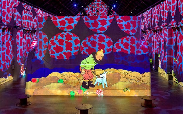 Digital art projection at Fabrique des Lumières featuring a cartoon character and dog.
