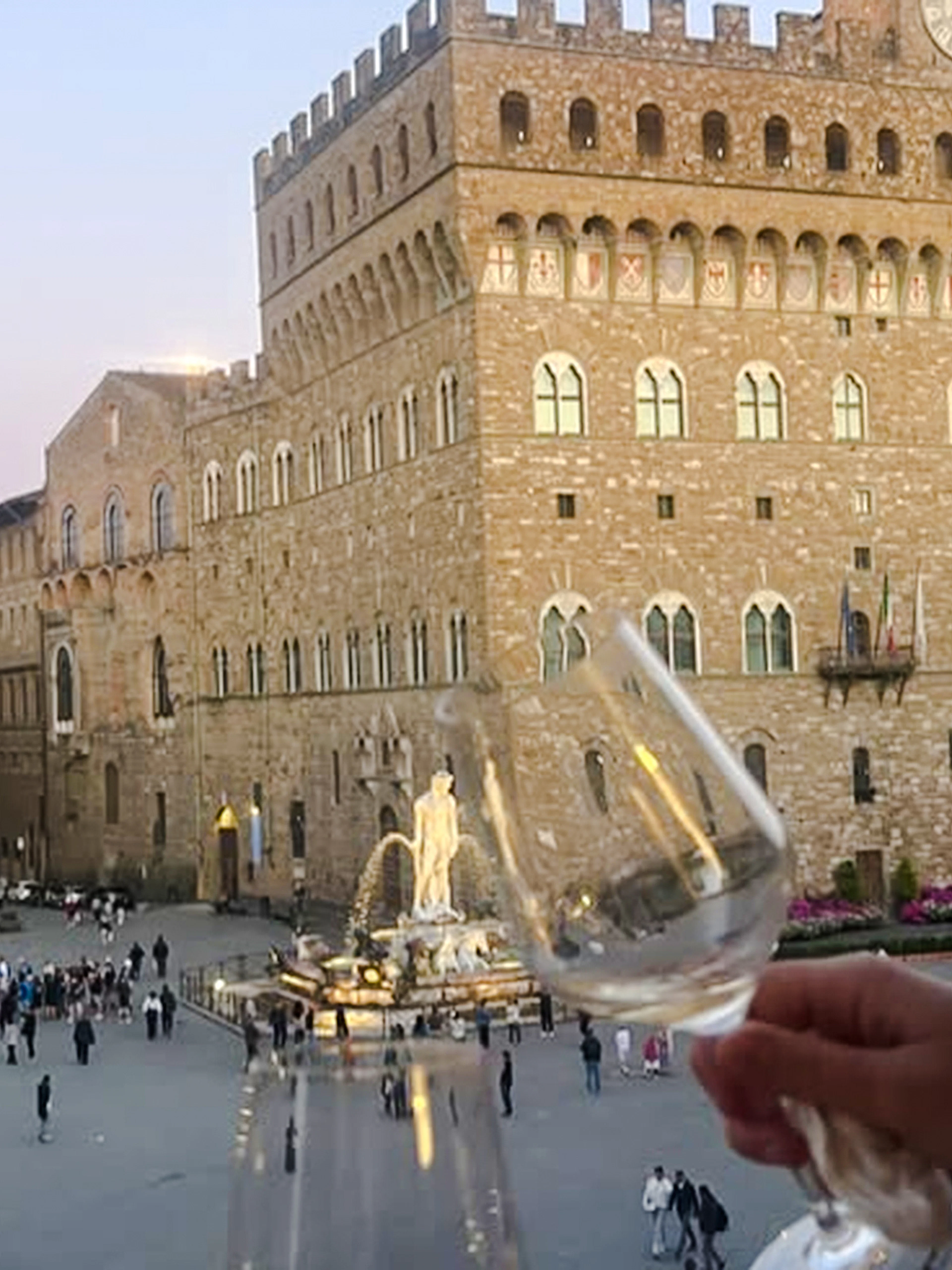 Wine glasses raised overlooking Piazza della Signoria in Florence, Italy.