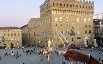 Wine glasses raised overlooking Piazza della Signoria in Florence, Italy.