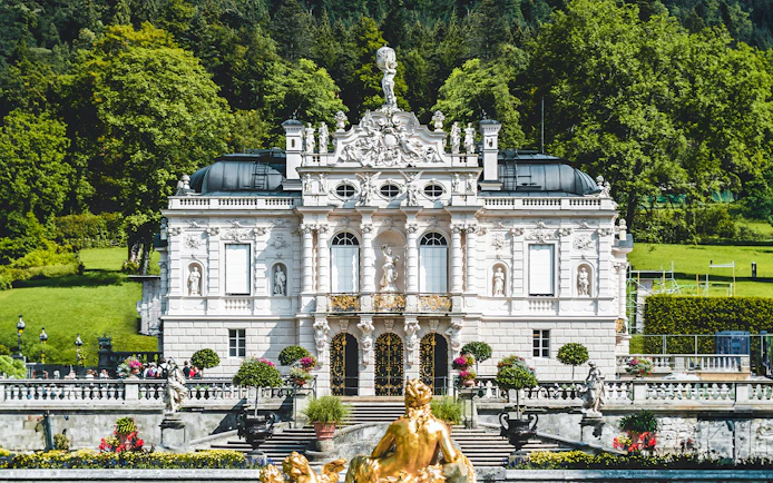 Linderhof Castle facade with ornate sculptures and manicured gardens in Bavaria, Germany.