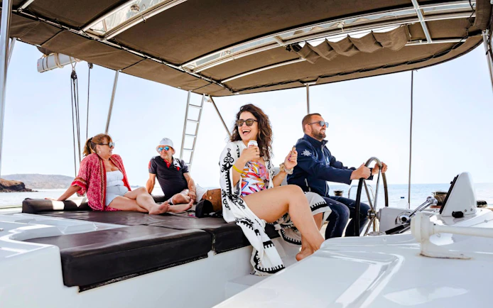 Guests relaxing on a catamaran during a cruise with meals and drinks.