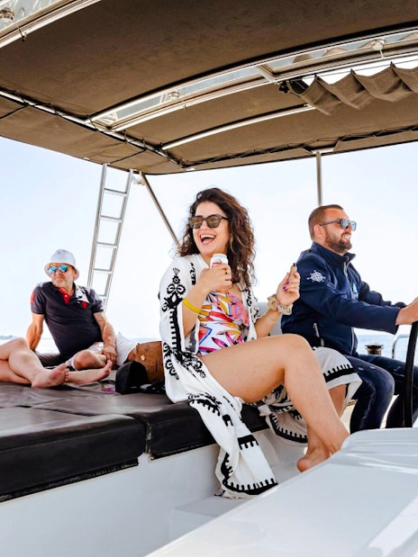 Guests relaxing on a catamaran during a cruise with meals and drinks.