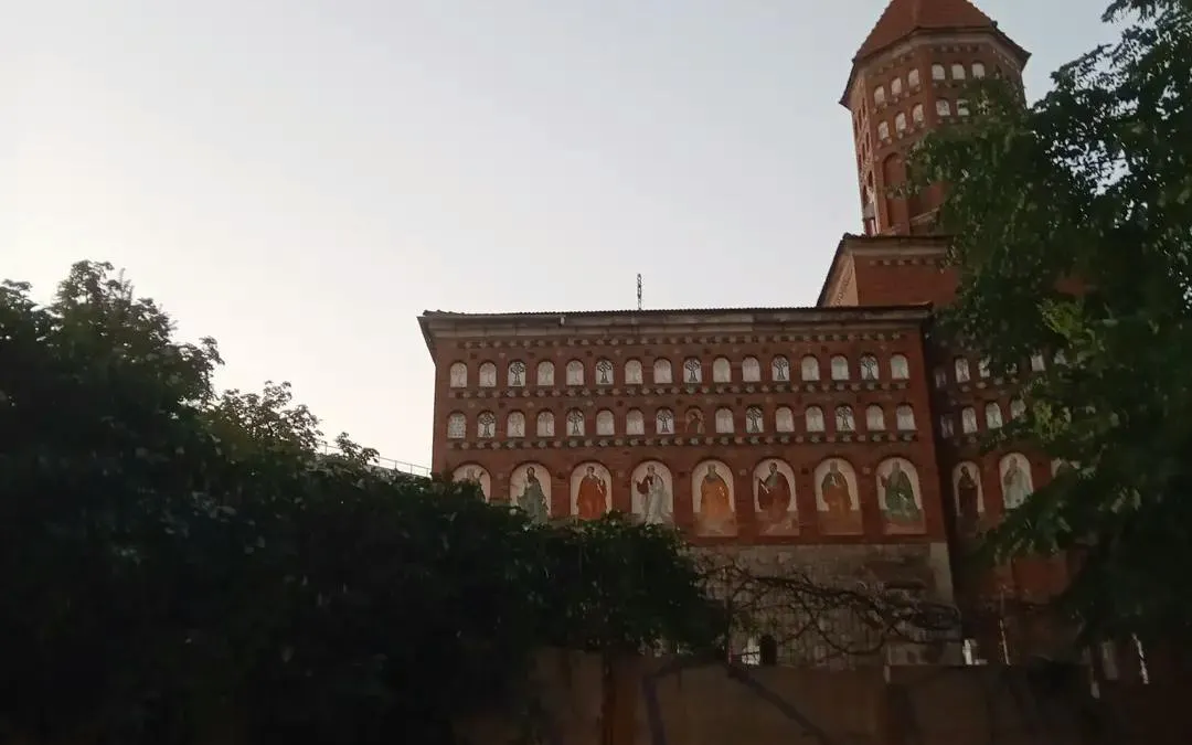 Red brick building with arched windows and frescoes in Carol Park, Bucharest.