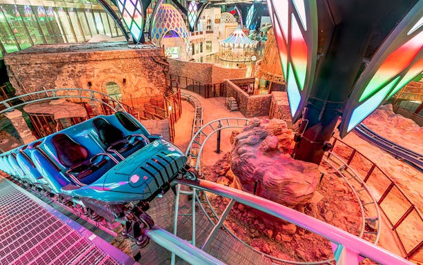 Doha Quest Theme Park indoor roller coaster with vibrant lights and futuristic design.