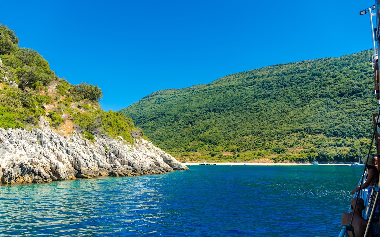Kakome beach coastline with lush green hills and clear blue water, viewed from a boat.