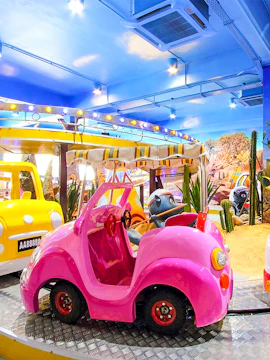 Pink toy car in a Wild West-themed indoor amusement ride with desert backdrop.