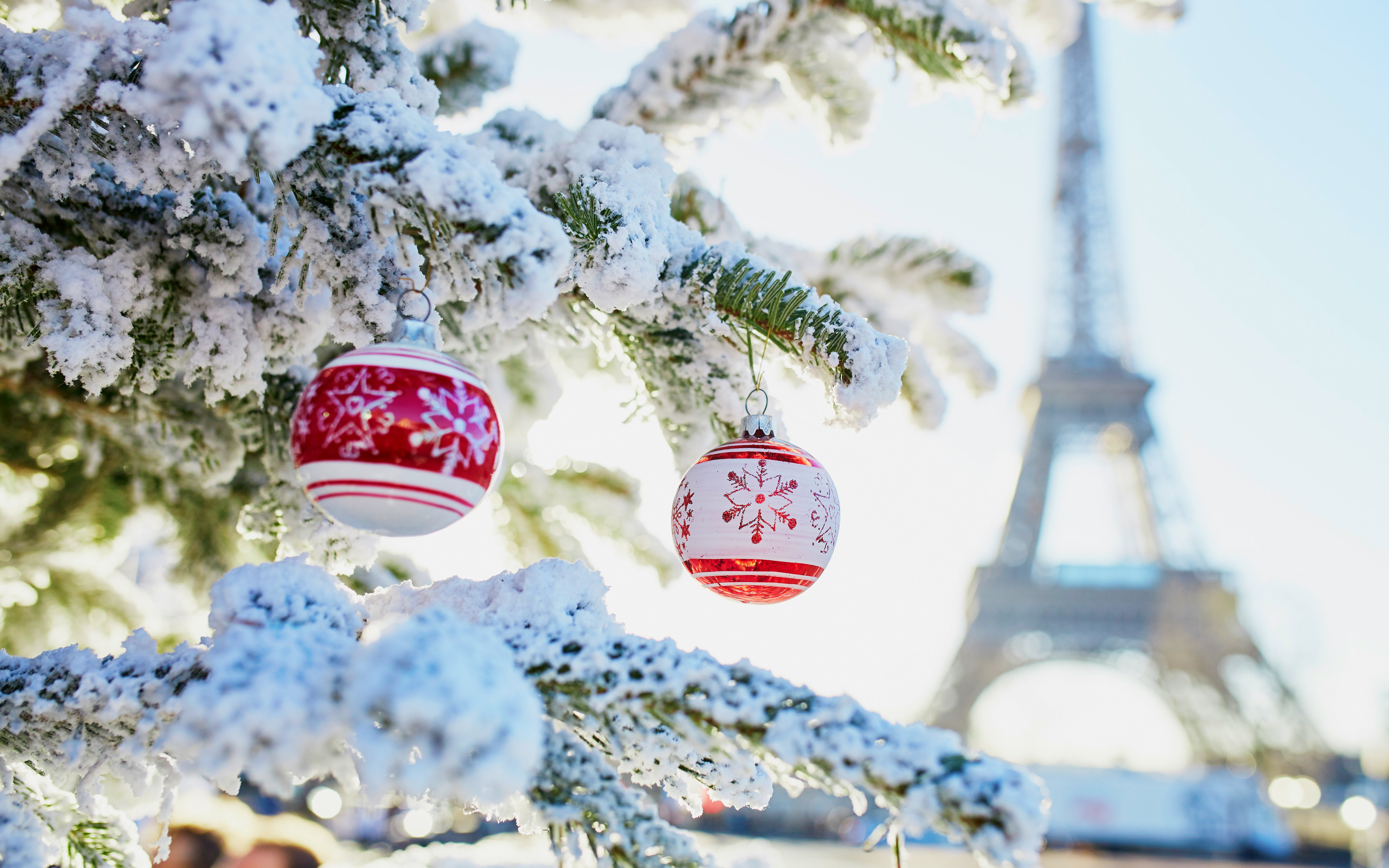 Snow-covered Christmas tree with ornaments near Eiffel Tower, Paris.