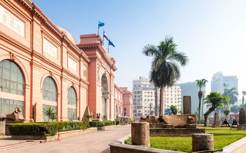 Egyptian Museum exterior with statues and palm trees, near Giza Complex, Cairo.