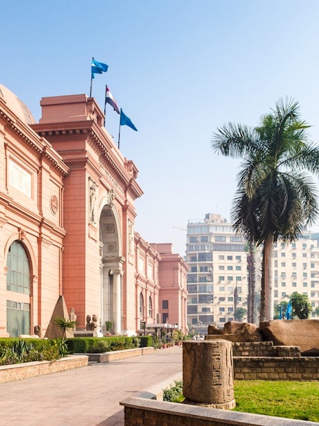 Egyptian Museum exterior with statues and palm trees, near Giza Complex, Cairo.