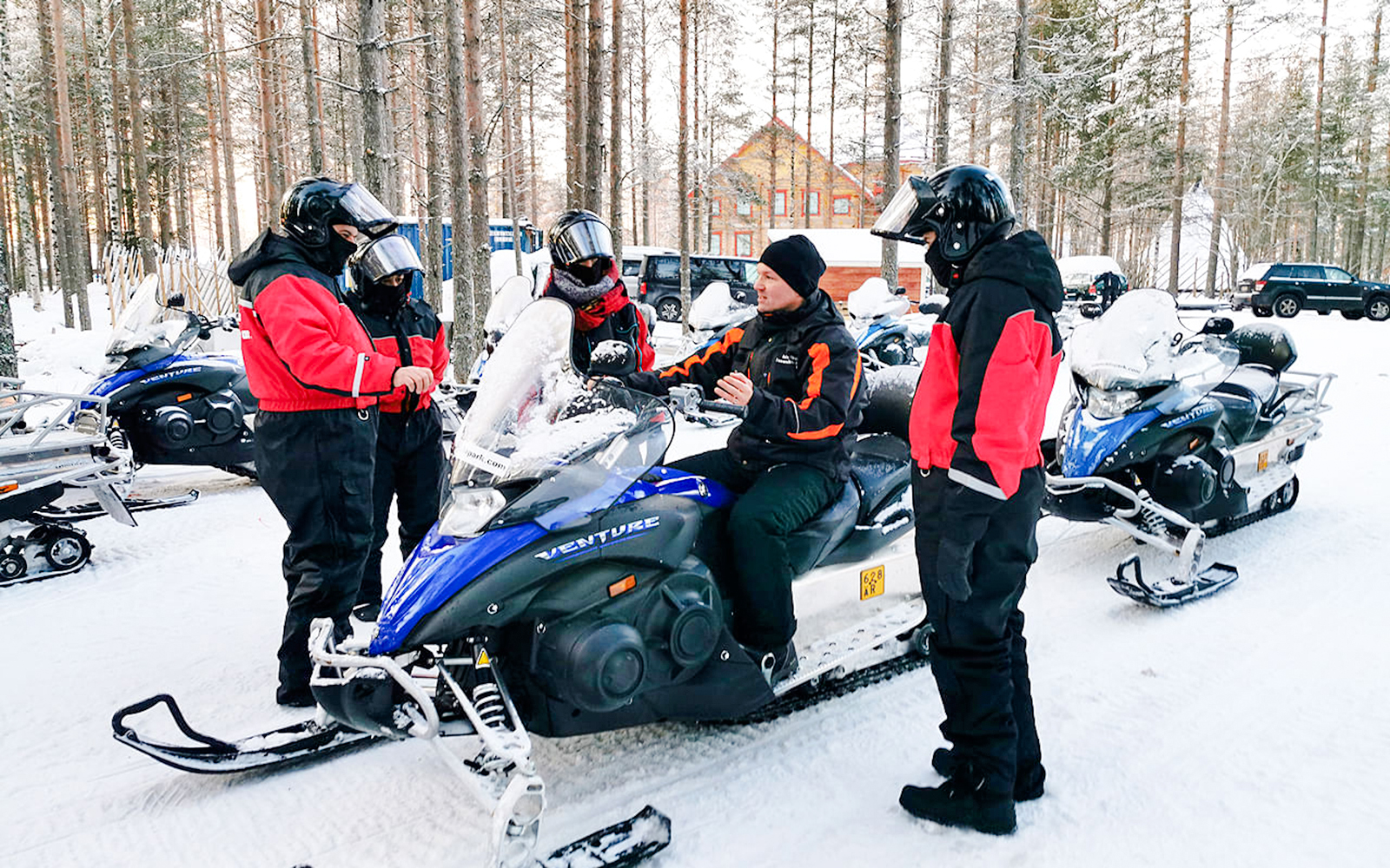 Group preparing for snowmobile tour in Rovaniemi forest.