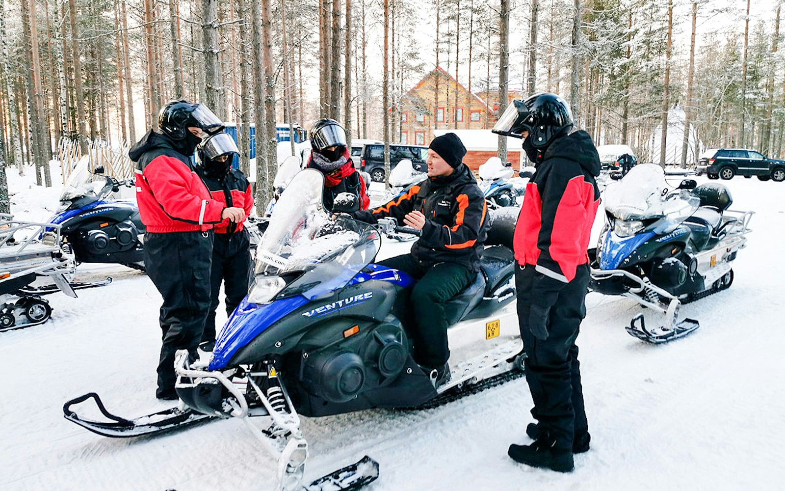 Group preparing for snowmobile tour in Rovaniemi forest.