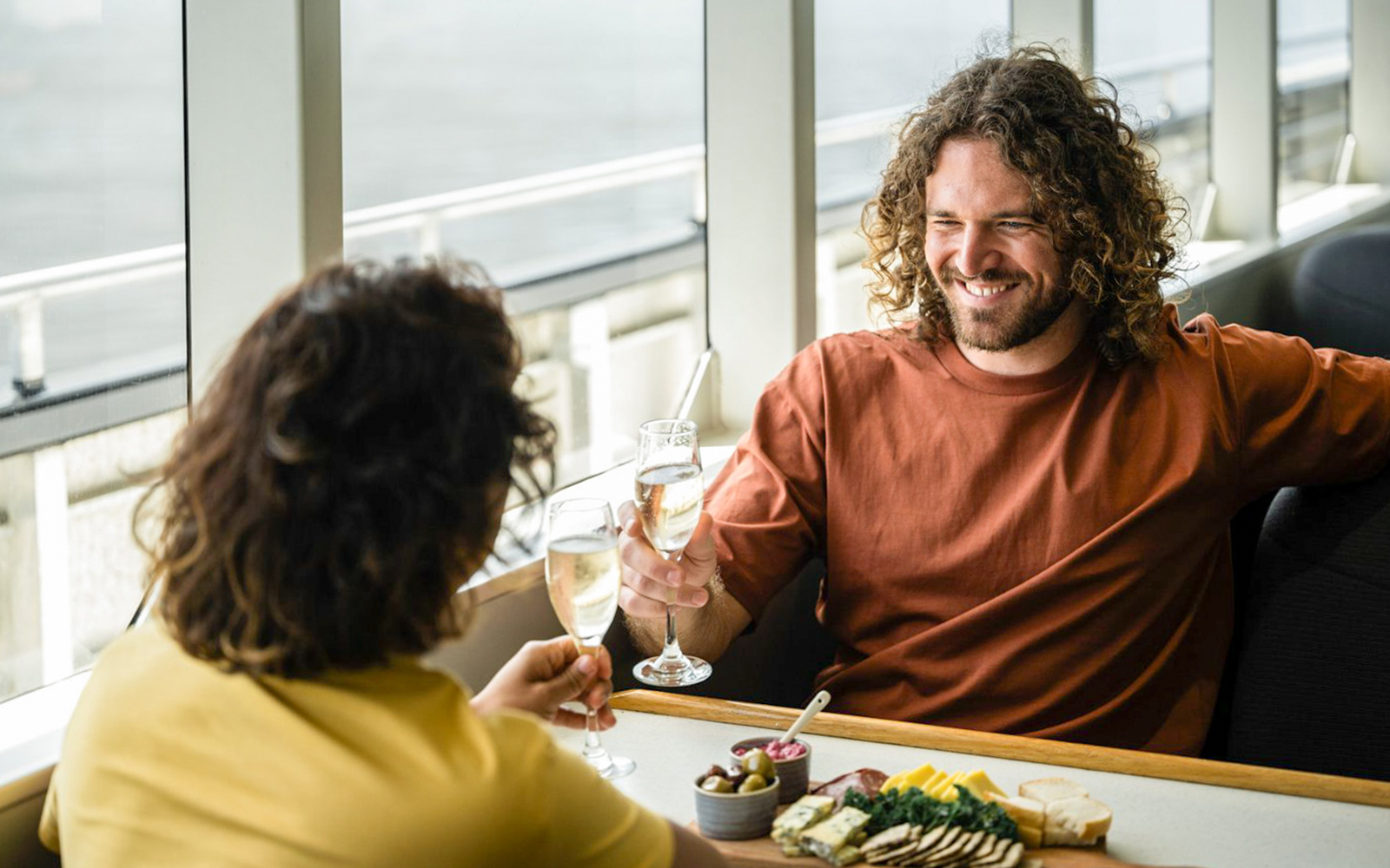 A couple enjoys a relaxed dining experience aboard a cruise in Doubtful Sound, toasting with glasses of champagne