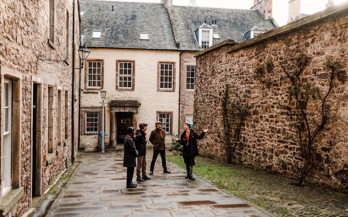 Tour guide leading a group through a historic alley on the Royal Mile in Edinburgh.