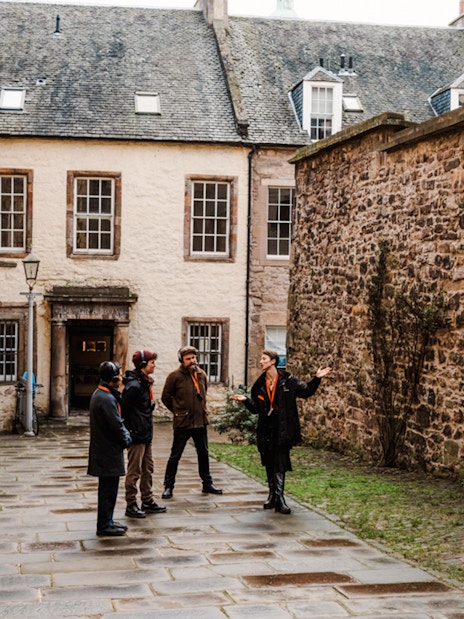 Tour guide leading a group through a historic alley on the Royal Mile in Edinburgh.