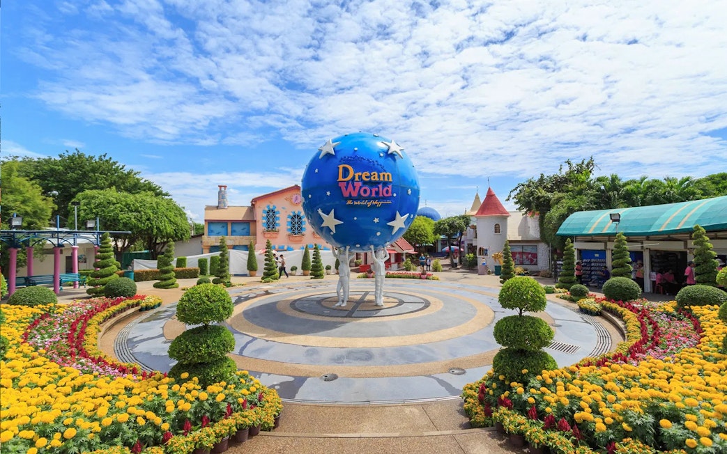 Dream World Bangkok entrance with globe sculpture and colorful gardens.