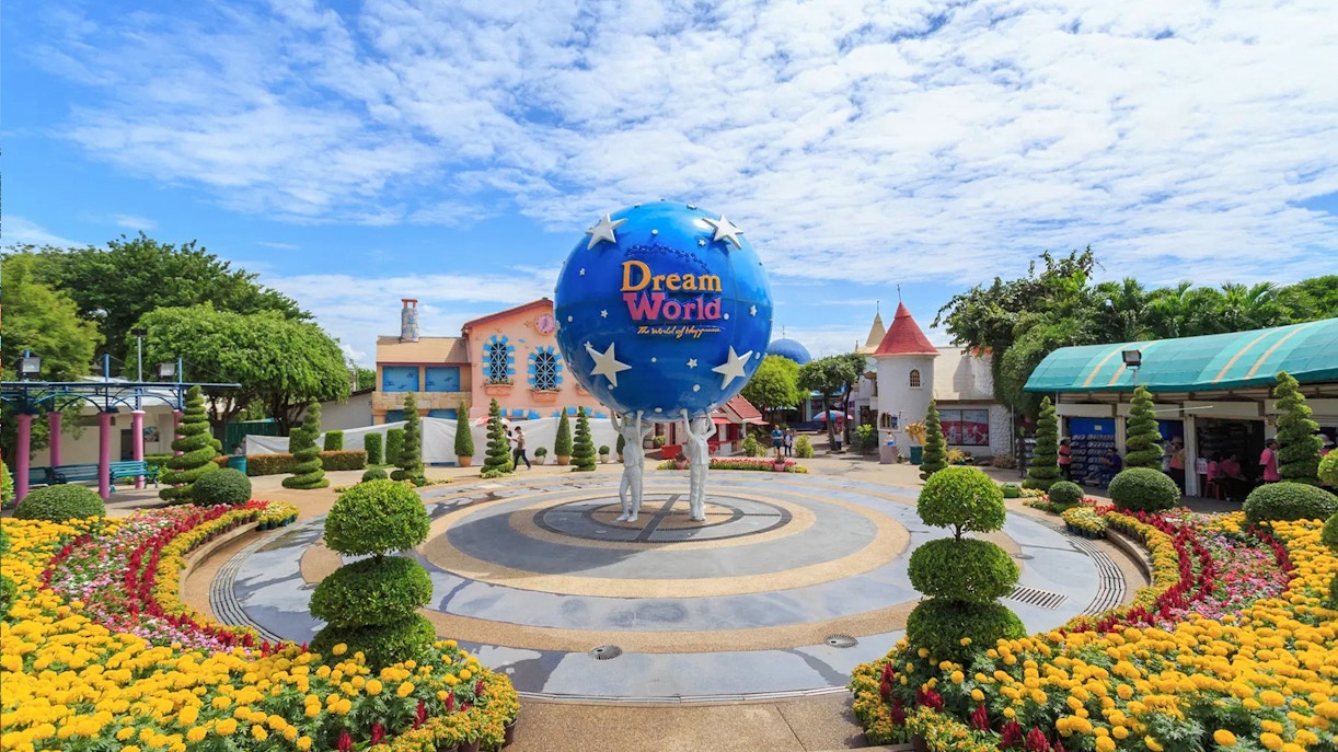 Visitors enjoying rides at Dream World Bangkok theme park with colorful attractions in the background.