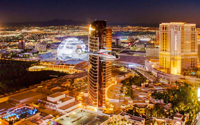 Helicopter flying over Las Vegas Strip at night with illuminated skyline.
