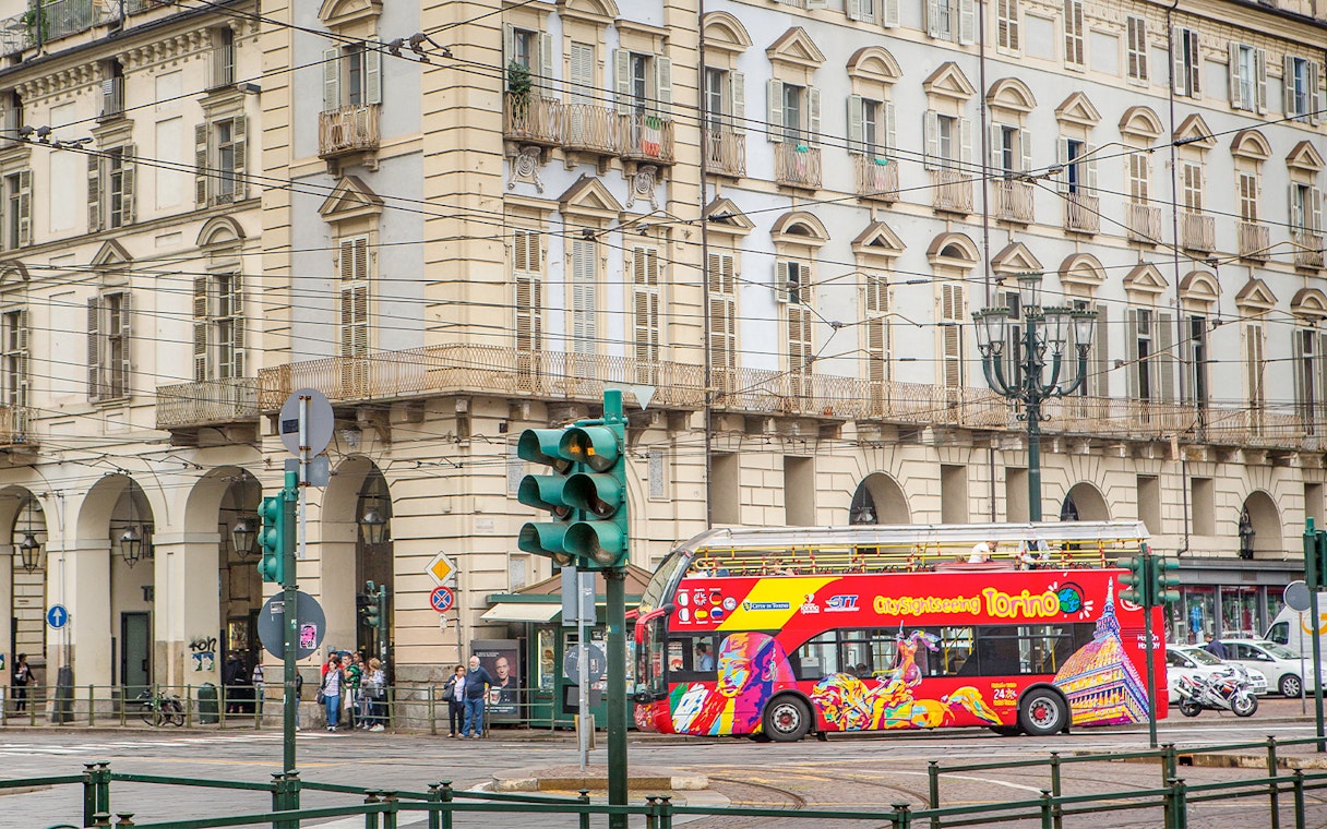 Turin hop-on hop-off bus passing historic building near Lavazza Museum.