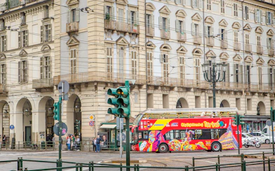 Turin hop-on hop-off bus passing historic building near Lavazza Museum.