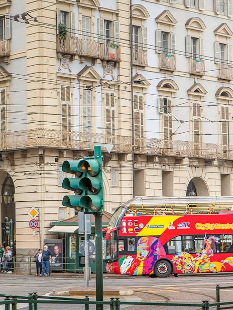 Turin hop-on hop-off bus passing historic building near Lavazza Museum.