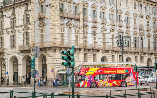 Turin hop-on hop-off bus passing historic building near Lavazza Museum.